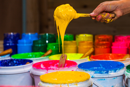 scoop yellow color of plastisol ink out the barrel in store. several colors of plastisol ink in tee shirt factory main color is blue green yellow orange red and black colorの写真素材