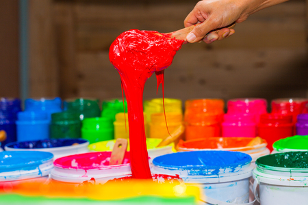 scoop red color of plastisol ink out the barrel in store. several colors of plastisol ink in tee shirt factory main color is blue green yellow orange red and black colorの写真素材