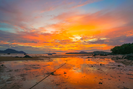 beautiful sunrise above fishing boats on the beach It creates a beautiful reflection in the water.
