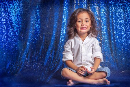 The boy sat in the blue glitter scene in studio to shoot the children's fashion.の写真素材