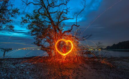 burning steel wool under mangrove tree in heart shape in twilight at Klong Mudong Phuket Thailand.の写真素材