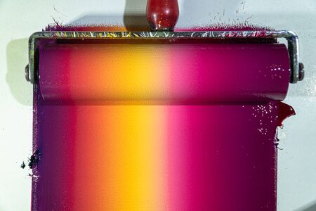 Mixing colors using a roller to rotate colors so that each color is blended together and then rolled onto the template to create graphic arts.の写真素材