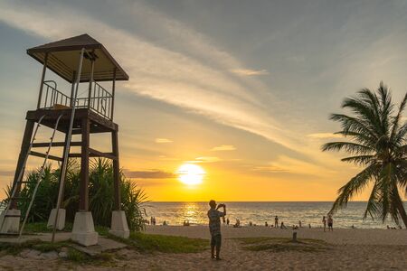 a man walking and take photo around lifegaurd tower during sunset at Karon beach Phuketの写真素材