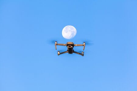 drone flying in front white moon in blue skyの写真素材