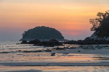 tourists are watching sunset on the rock at Kata beach Phuketの写真素材