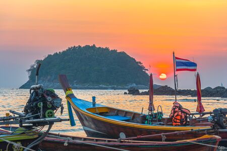 round red sun in sunset above fishing boats in Kata beach Phuket Thailandの写真素材