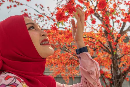 beautiful islamic lady enjoy with red Sakura in the park of center square in Bangkok