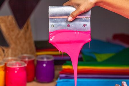 pink color dripping from hand screen printing during printing tee shirt in tee shirt factory.