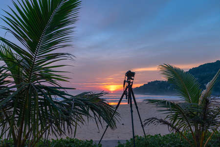 the camera stand on the beach to take a photo of sunset