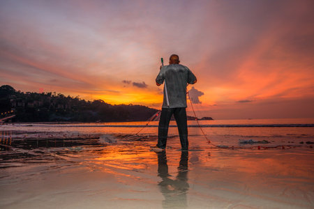 People come out to trawl their nets on Patong beach during sunset timeの写真素材