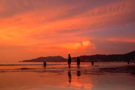 People come out to trawl their nets on Patong beach during sunset timeの写真素材