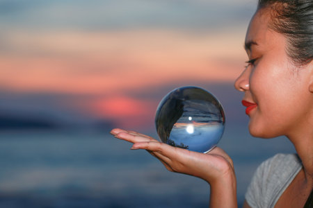 lady put the crystal ball on her hand beside Patong beach during sunsetの写真素材