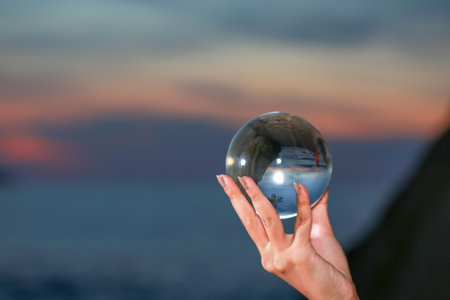 Holding a crystal ball in hand at twilight beside the beach