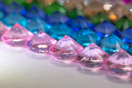Colorful diamonds are arranged neatly in a row on a white floor.
