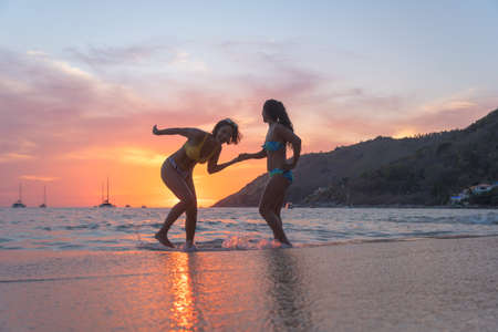 Two women playing on the beach in the beautiful sky.の写真素材