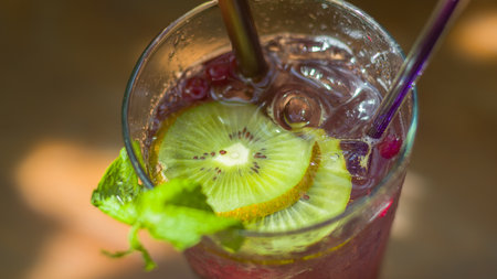 Grape juice, kiwi and soda put ice in a transparent glass.The backdrop of a waterfall, lush...