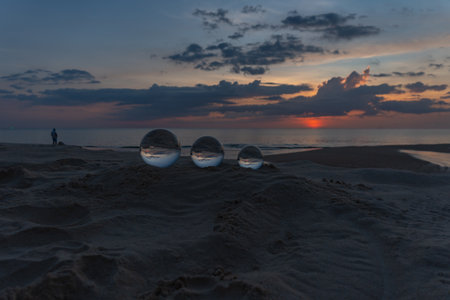 Three clear crystal balls of three sizes are sphere reveals  seascape view with spherical 
placed on the sand at Karon Beach during sunset.の写真素材