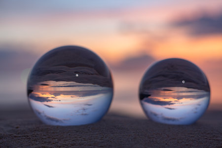 Three clear crystal balls of three sizes are sphere reveals  seascape view with spherical 
placed on the sand at Karon Beach during sunset.の写真素材