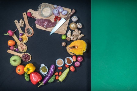 Fresh meats, vegetables and spices are laid out on a food prep table covered with a black tablecloth.
With green cloth covering the sides.の写真素材