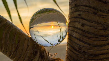 sunset sunrise view inside crystal ball placed on the forks of a branch.
The natural view of the sea and sky are unconventional and beautiful. 
A image for a unique and creative travel idea.の写真素材