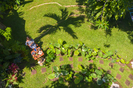 A woman holding a glass of hot coffee in green garden. 
A woman relax in green garden with coffee set on wooden table. 
green garden background.の写真素材