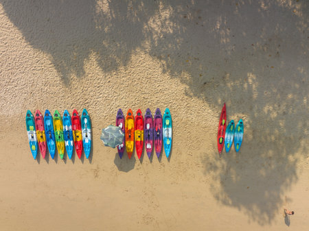 Aerial top view Colorful canoes are lined up in front of the beach.The clear green sea water can be seen through the sea.green sea white sand beach footage for creative nature and travel concept.の写真素材