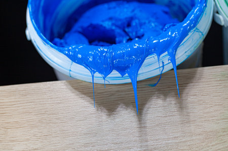 Blue paint dripping from white barrel.
plastisol ink is used for printing on fabrics because it is durable,
 easily cured and can be stretched without cracking or becoming distorted.の写真素材