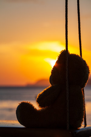 lonely Teddy Bear sitting on a swing in front Rawai beach to see sunrise.
scenic reflection of beautiful sunshine above fishing boats are floating in the Rawai sea.
beautiful golden sky background.の写真素材