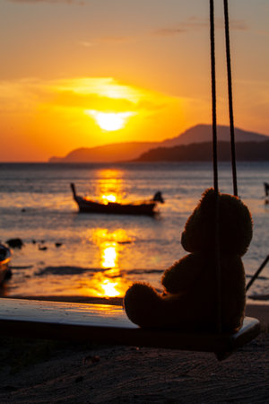 lonely Teddy Bear sitting on a swing in front Rawai beach to see sunrise.
scenic reflection of beautiful sunshine above fishing boats are floating in the Rawai sea.
beautiful golden sky background.の写真素材