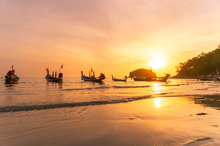 The sun above the island in the yellow sky.Fishing boats lined up on the beach in The yellow sky reflects on the surface of the waves.の写真素材
