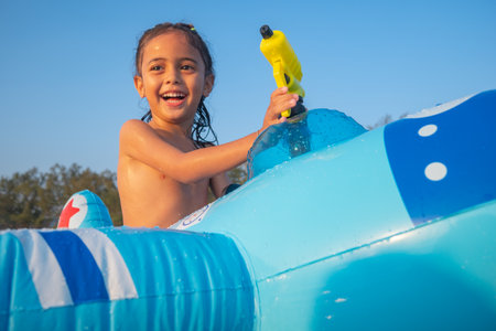 A boy plays with a water gun on a blue rubber ring in the shore. He also enjoys the feeling of the...