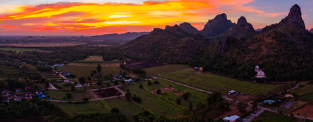 Aerial view of a beautiful view of a long, colorful mountain range and a field under a bright sunset sky. This image captures the natural beauty, tranquility and charm of the countryside.の写真素材