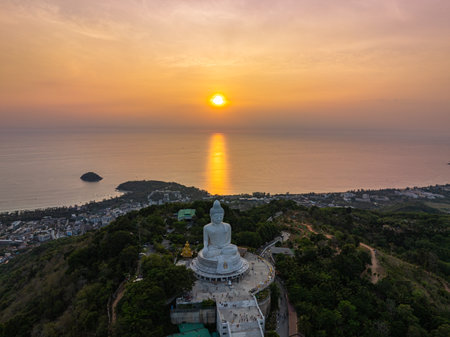 aerial view bright yellow sun in sunrise at Phuket big Buddha. the sun breaks through the clouds and illuminates the Buddha statue that atop the mountain.Sunrise with amazing light rays effects.の写真素材