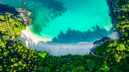 Forest shadows cast over the beach in the morning. A small white beach hidden in the jungle and green sea. It is difficult to visit. It is near the famous tourist attraction Patong.の写真素材