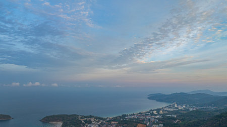 Aerial view A breathtaking view of a coastal city at sunset, with golden hues illuminating the sky and reflecting on the calm ocean. Small islands and boats are visible in the distanceの写真素材