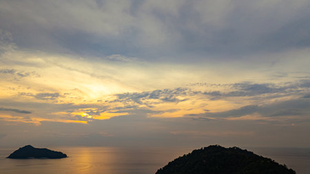 Aerial view of a stunning sunset above the Surin Islands. With golden hues reflecting on the calm ocean waters. The coral reef at the shoreline in the foreground adds depth. Paradise for snorkelの写真素材