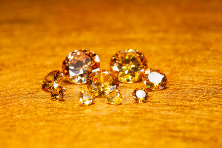Yellow sapphires are arranged on a golden yellow velvet cloth. The sapphire sparkles beautifully. The diamonds are valuable and luxurious.の写真素材