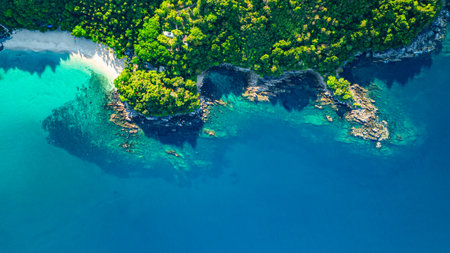 A breathtaking aerial view of a secluded Freedom beach with crystal-clear turquoise waters, surrounded by lush green vegetation and rocky cliffs. The pristine white sand and vibrant ocean huesの写真素材