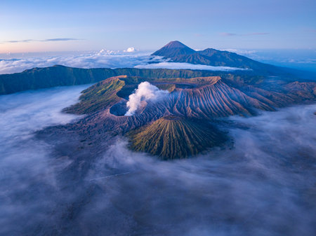 aerial view of breathtaking Mount Bromo surrounded by mist and dramatic landscapes. an active volcano in Indonesia, The soft morning light highlights the rugged terrain and the rising volcanic smoke,の写真素材