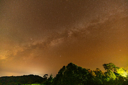 Time lapse Milky Way above mountains at night in autumn. Landscape with mountain valley, low clouds, purple starry sky with milky way. The Milky Way shines on a cold night in the north of Thailandの写真素材