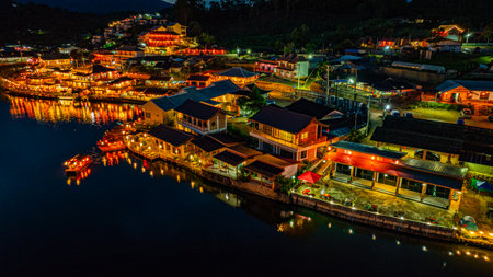 At dusk the reflections of the lights from the village the lake in Chinese-style structures with colorful lights lined the waterfront. Ban Rak Thai is a popular tourist attraction in Mae Hong Sonの写真素材