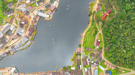 aerial top view of a lakeside village, showcasing a mix of rustic architecture, lush greenery, and...