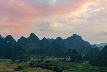 A breathtaking aerial view of a dramatic sunrise illuminating the sky with vibrant orange and red hues over mist-covered karst mountains. The serene landscape, dotted with valleys and rivers,の写真素材