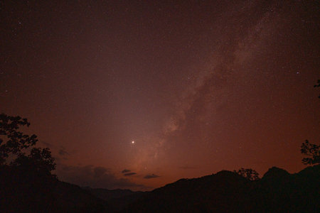 Milky Way above mountains at night in autumn. Landscape with mountain valley, low clouds, purple starry sky with milky way. The Milky Way shines on a cold night in the north of Thailandの写真素材