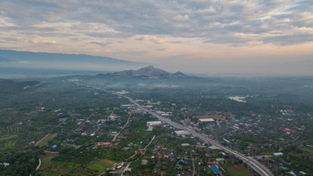 A stunning aerial view of a winding river flowing through a vast rural landscape at dawn. The soft morning light and misty atmosphere create a tranquil and picturesque scene, with scattered villagesの写真素材