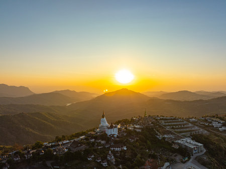 Aerial view amazing Big White Five buddha Statues in Wat Phra Sorn Kaew temple. The sun shone on the edge of the mountain, casting a golden glow on the ornate statue. Stands elegantly on the hill.の写真素材
