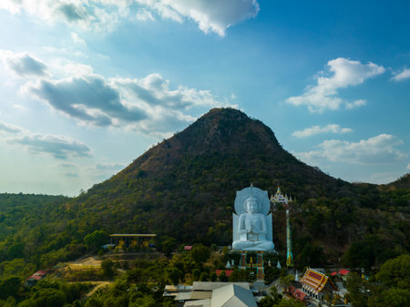 A majestic large sitting Buddha statue meditating amidst lush green hills and natural light. This peaceful place showcases the harmony of sacred architecture and natural beauty. mountain backgroundの写真素材