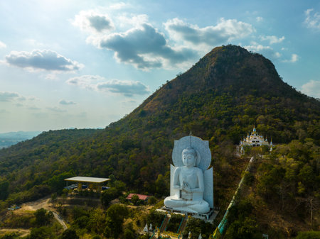 A majestic large sitting Buddha statue meditating amidst lush green hills and natural light. This peaceful place showcases the harmony of sacred architecture and natural beauty. mountain backgroundの写真素材