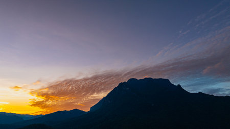 A breathtaking aerial panoramic view of a vibrant sunset illuminating the sky above a lush green...