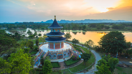 aerial photo beautiful pagoda in Chinese style beside river at Wat Yuan Kanchanaburi. The scene blends cultural heritage with natural beauty and urban development.の写真素材
